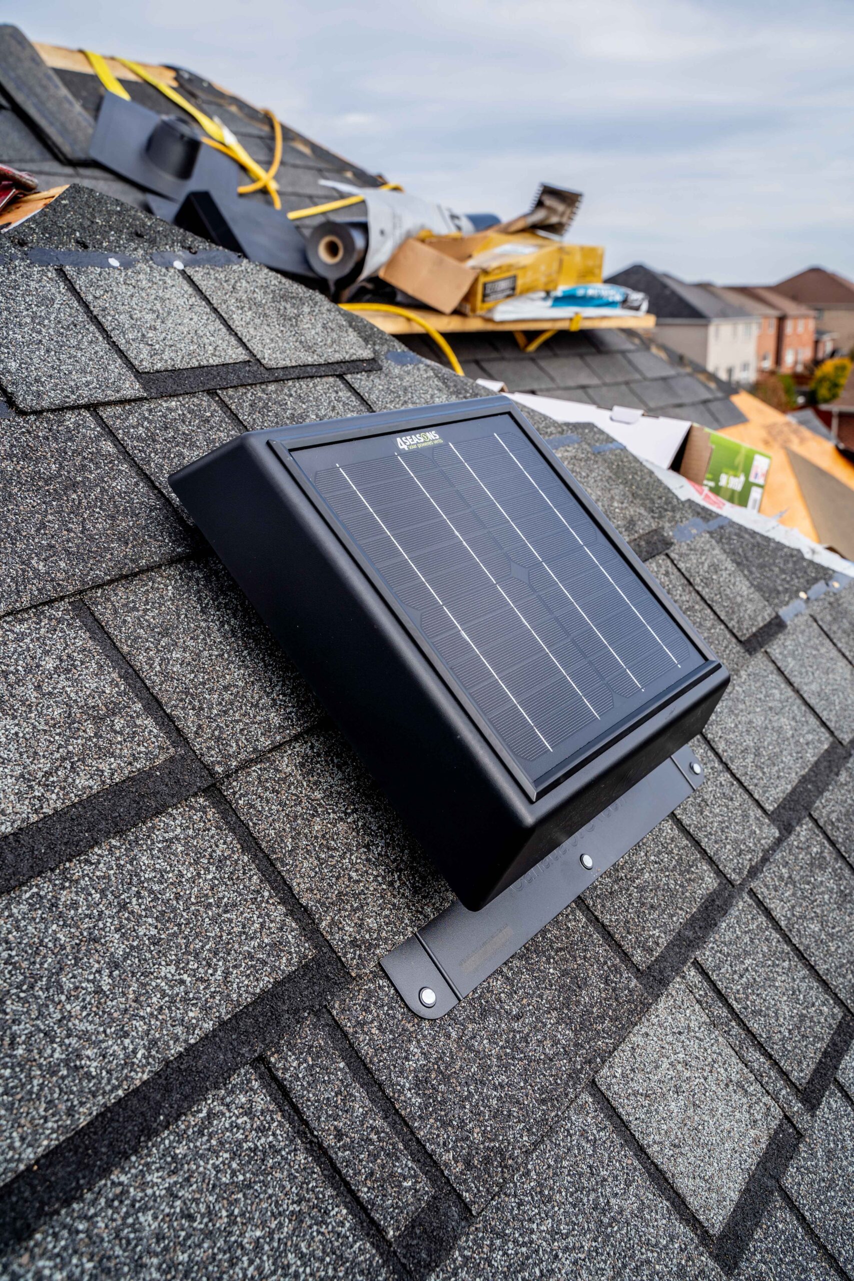 Solar-powered attic fan mounted on a shingle roof actively venting attic air