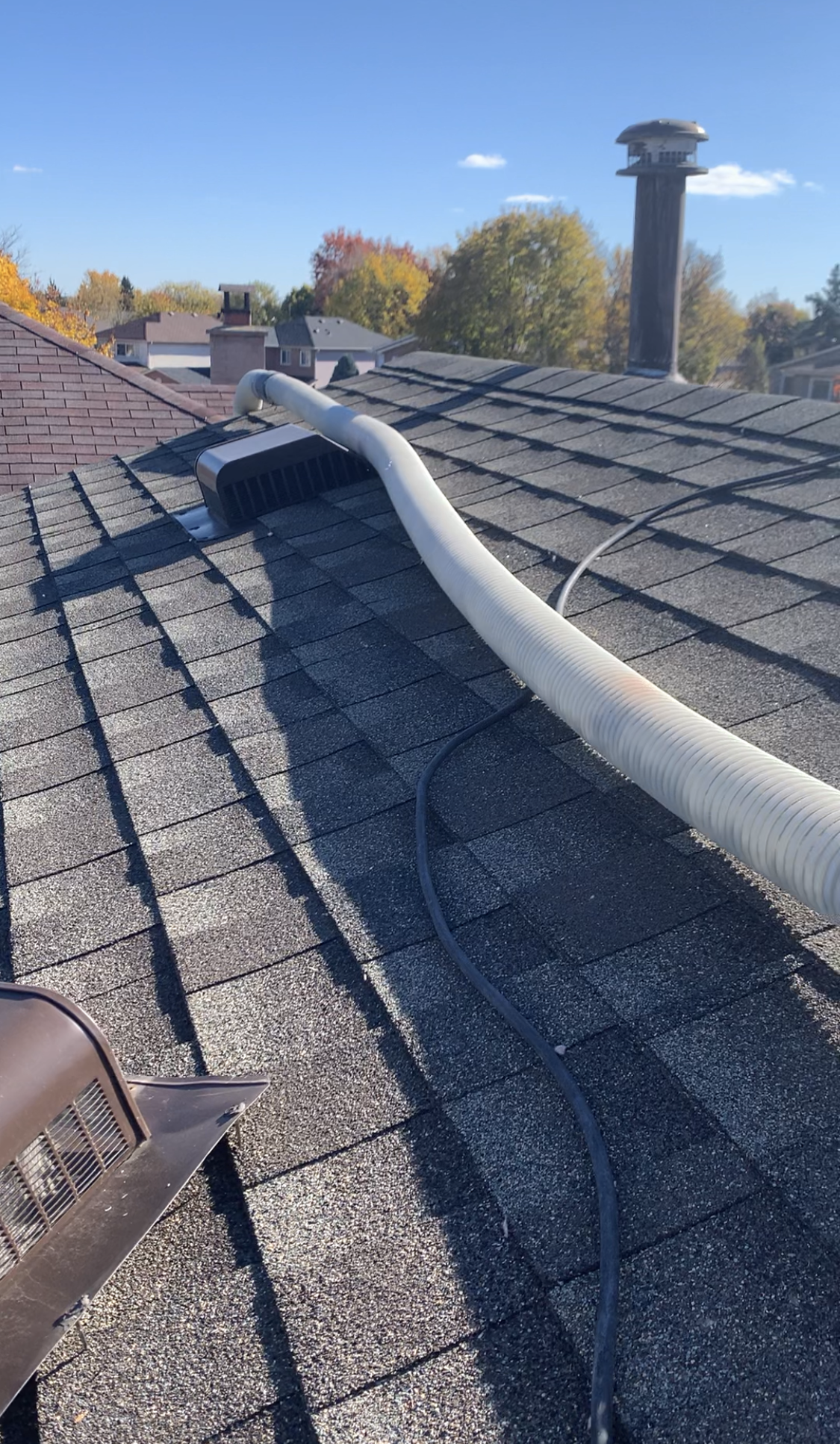 Insulation delivery hose routed directly into attic via rooftop vent opening